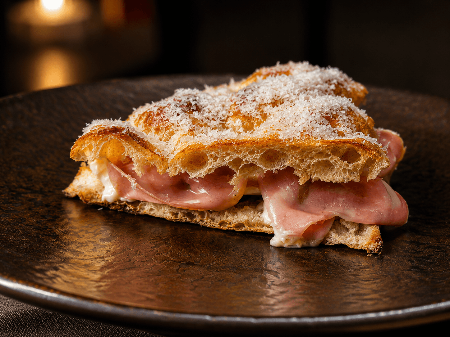 Focaccia farcita con mortadella e parmigiano grattugiato su piatto artigianale